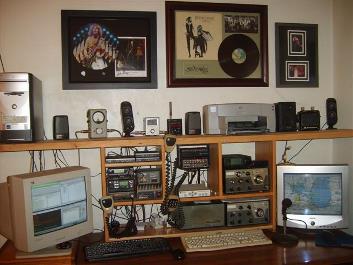 A multi-radio amateur station and BBS setup with computer, monitors, and several transceivers on a desk.