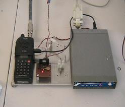 A low-power VHF packet node built from a handheld transceiver and small TNC, wired to a solar-powered installation.